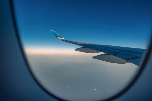 Ala de silueta de un avión al amanecer vista a través de la ventana . —  Fotos de Stock