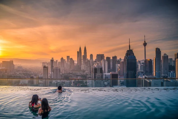 쿠알라룸푸르, 말레이시아에서 일출 보기 스카이 라인 쿠알라룸푸르 시티 호텔의 옥상에 수영장에 보고 하는 여행자. — 스톡 사진