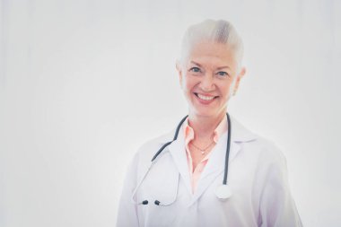 Beyaz arka planda duran kıdemli kadın doktorun portresi.