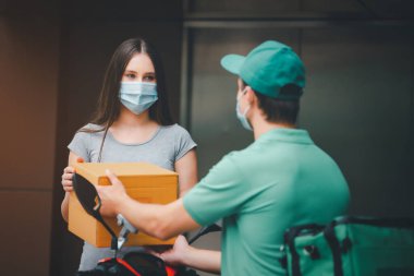 Yeşil kapşonlu tişörtlü teslimatçı eleman yemek kutusunu gümrük ofisinin önüne göndermeye hazır. Teslimat ve alışveriş online konsepti.