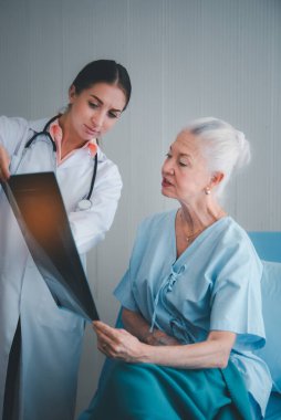 Kadın doktor röntgen filmi sonuçlarını gösterip hastanedeki yaşlı hastalara sağlık sorununu açıklıyor. Sağlık hizmetleri ev bakımı kavramı