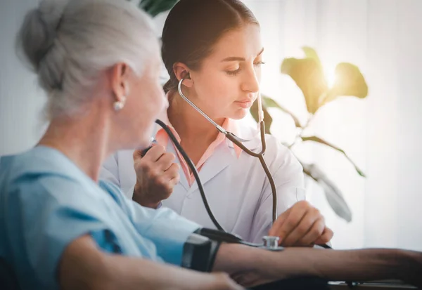 Happy Elderly patient talk with woman doctor at room in hospital. Doctor use stethoscope listening lung of elderly patient. Healthcare homecare concept