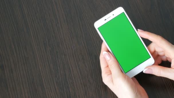 Eller güzel Fransız manikür ile yeşil ekran ile beyaz bir akıllı telefon alıyorum. Smartphone, Holding Smartphone bir şık siyah ahşap masa üstünde yeşil perde ile kullanma — Stok video