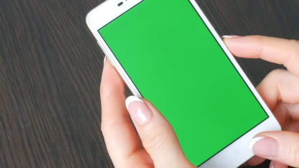 Ženské ruce s krásnou francouzskou manikúru si bílý smartphone s Green Screen. Pomocí Smartphone, držení Smartphone s Green Screen na stylový černý dřevěný stůl — Stock video