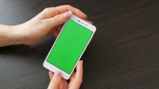 Frauenhände mit schöner französischer Maniküre nehmen ein weißes Smartphone mit grünem Bildschirm. Smartphone benutzen, Smartphone mit grünem Bildschirm halten — Stockvideo