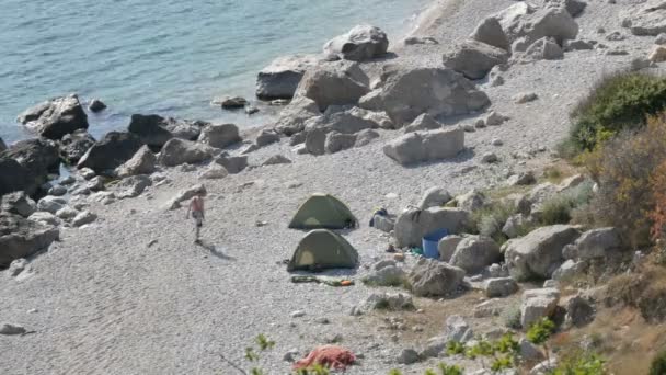 Rotsachtige kust van de Zwarte Zee waarop er weinig mensen met tenten zijn. Kamperen in het wild plaatsen — Stockvideo