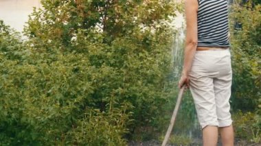 Kadın bir hortum dan onun bahçede bitkilerin sulama