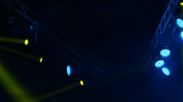 Luz azul y amarilla en el escenario. Soffits brillan en un concierto. La luz luminosa del escenario parpadea en el humo — Vídeos de Stock