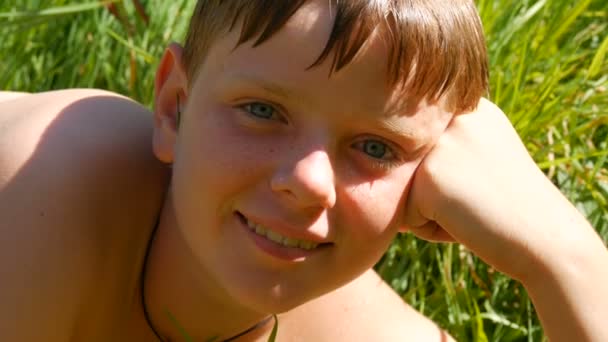 Портрет милого рыжеволосого подростка после купания в реке летом. Мальчик-подросток с веснушками и голубыми глазами, смотрящий в раму и счастливый улыбающийся — стоковое видео