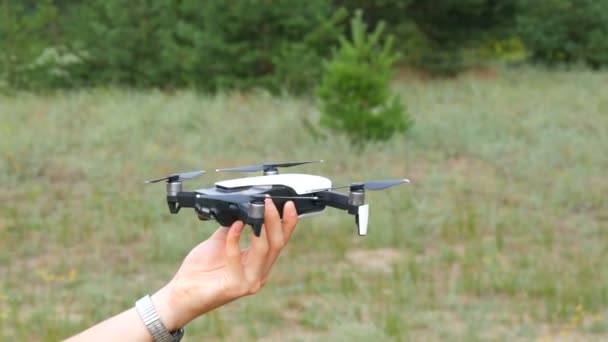 A mans ręce trzyma drone lub drona na tle zielonego lasu. Technologie przyszłości — Wideo stockowe