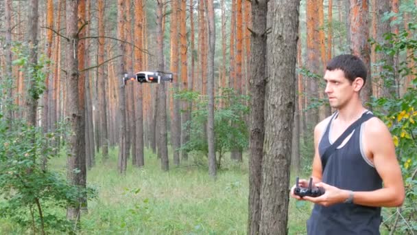 Lindo hombre alto lanza dron o quadrocopter en el bosque — Vídeo de stock