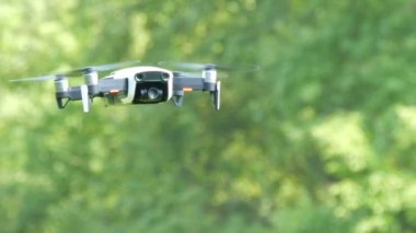 Bir dron veya quadrocopter beyaz renk yeşil orman arka planı havada uçar. Geleceğin teknolojileri