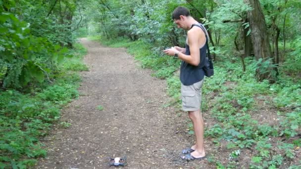 Netter großer Mann startet Drohne oder Quadrocopter im Wald — Stockvideo