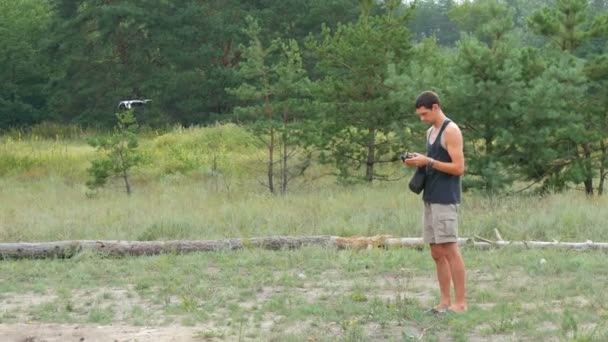 Ein niedlicher großer Mann startet und hält eine Drohne oder einen Quadrocopter im Wald — Stockvideo