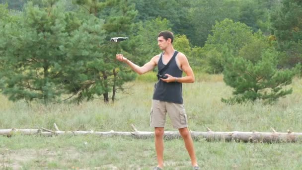 Netter großer Mann startet und hält Drohne oder Quadrocopter im Wald — Stockvideo