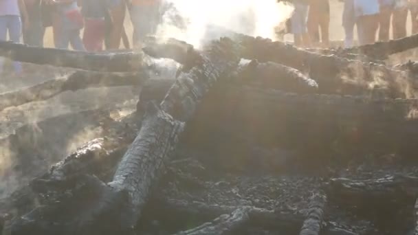 Bis auf die Kohlen verbrannt, schwarze Bäume rauchen vor dem Hintergrund der Füße der Menschen — Stockvideo