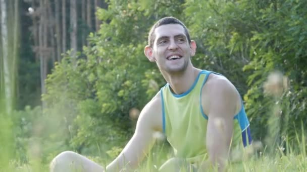 Jovem sentado na natureza na grama feliz apreciando a vida e sorrindo — Vídeo de Stock