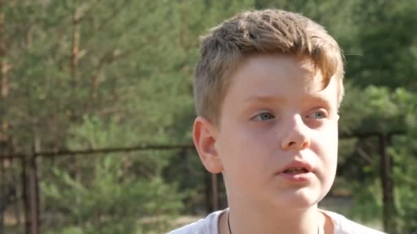 Un adolescent est assis dans un parc d'été forestier à côté d'un vélo et regarde la caméra 