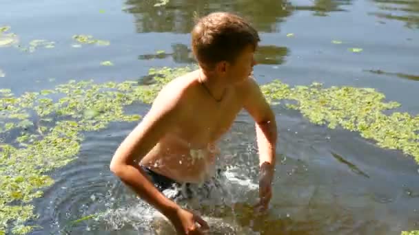 Adolescente chico está bañándose en un río salvaje en el verano. Hierba en el río en condiciones naturales naturales — Vídeo de stock