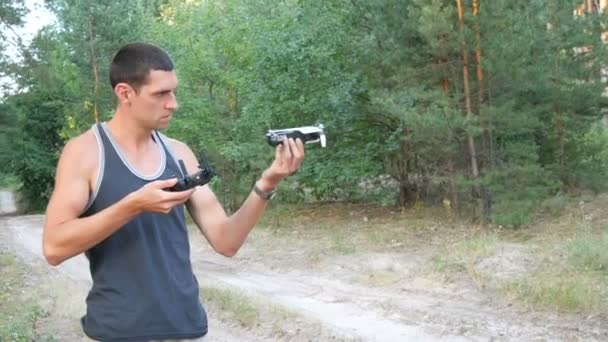 Cute tall man launches drone or quadrocopter in the woods — Stock Video