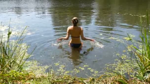 Een jonge vrouw baadt in een wilde rivier in de zomer. Kroos op de rivier in natuurlijke natuurlijke omstandigheden — Stockvideo