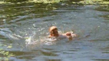 Genç çocuk vahşi bir nehirde yaz aylarında yüzme. Duckweed doğal doğal koşullarda Nehri üzerinde