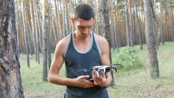 Lindo hombre alto lanza dron o quadrocopter en el bosque — Vídeos de Stock