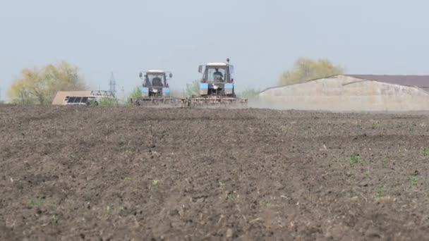 Deux tracteurs travaillent sur le terrain au début du printemps — Video