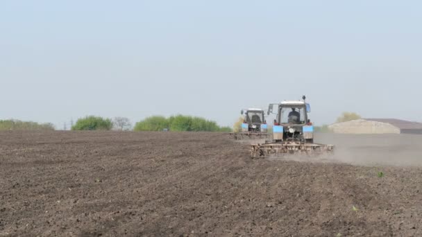 Два трактора работают в поле ранней весной — стоковое видео