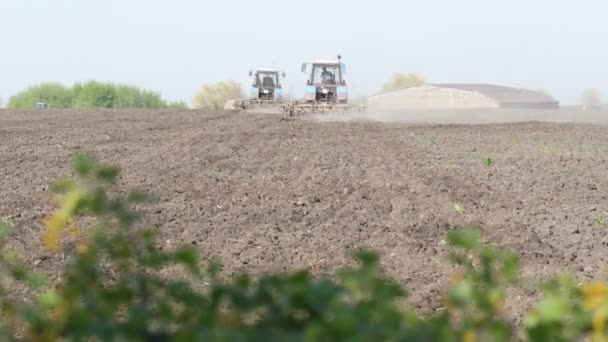 Два трактора работают в поле ранней весной — стоковое видео