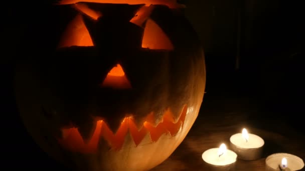 Terrible calabaza de Halloween rodeada de muchas velas en la oscuridad — Vídeo de stock