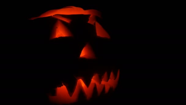 暗闇の中ですべての聖徒の日にハロウィンのカボチャに彫られた明るい顔をしかめる — ストック動画