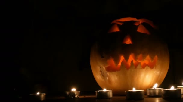 Abóbora terrível Halloween cercada por muitas velas no escuro — Vídeo de Stock