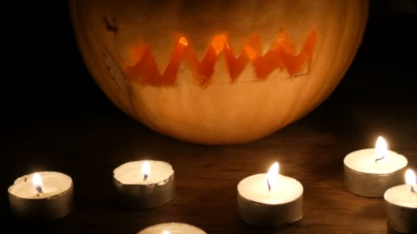 Hemska Halloween pumpa omgiven av många ljus i mörkret — Stockvideo
