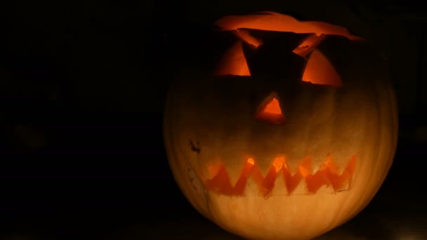 Lysande grimas ristade på Halloween pumpa att de dag av alla heliga i mörkret — Stockvideo