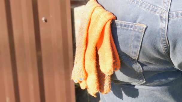 Oranje bouw handschoenen in de broek in een achterzak van de werknemers-jeans — Stockvideo