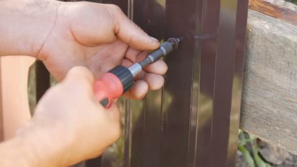 Męskie dłonie naprawić ogrodzenie z specjalne śruby i wkrętak ręczny — Wideo stockowe