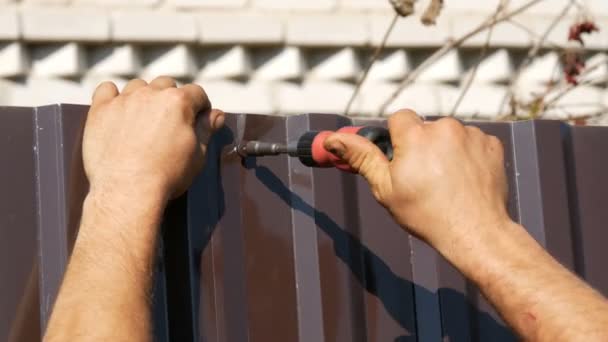 Male hands fix the fence with special screws and manual screwdriver — Stock Video