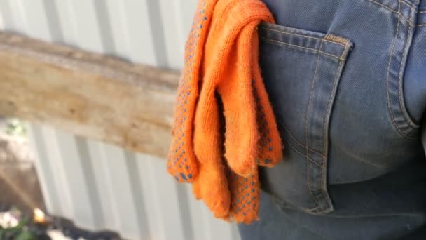 Orange konstruktion handskar i byxorna i en bakficka av arbetstagare jeans — Stockvideo