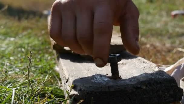 Los dedos masculinos hacen girar una tuerca en tablero de madera — Vídeo de stock