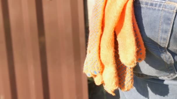 Guantes de construcción naranja en los pantalones en un bolsillo trasero de los pantalones vaqueros de los trabajadores — Vídeos de Stock