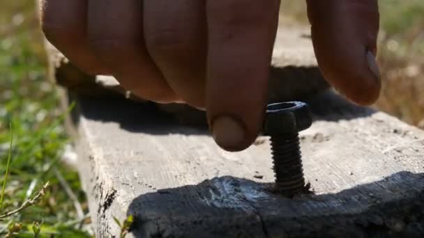 Male fingers spin a nut into wooden board — Stock Video