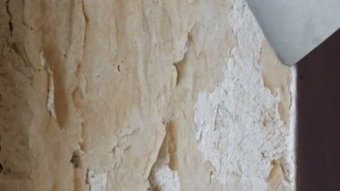 Adam özel spatula ile eski duvar kağıdı soyulması. Sarı, eli ayağı tutmaz duvar kağıdı duvar ev onarım yakın çekim