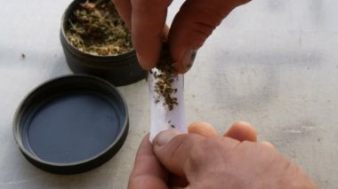 İnce kağıt ve rendelenmiş tütün plastik bir çanta dışarı alarak ve kendini beyaz bir arka plan üzerine bir sigara haddeleme adam görünümü kapatın