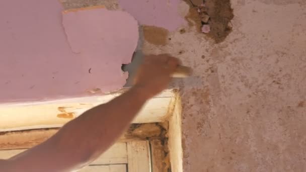 집 수리. 남성 손 벽에서 분홍색 오래 된 벽지 특별 주걱으로 껍질 — 비디오