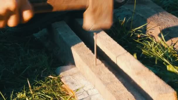 Man hammering used long nail into old boards — Stock Video