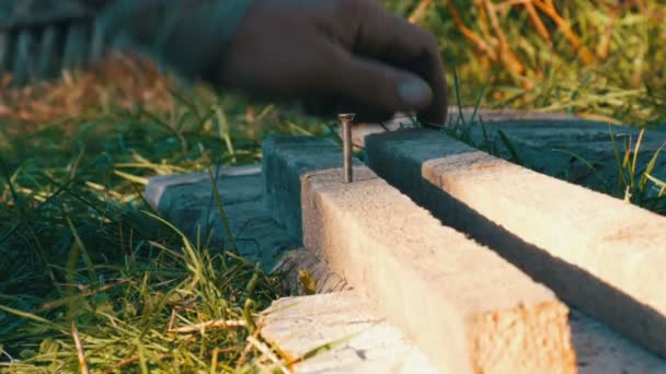 Man hammering used long nail into old boards — Stock Video