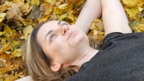 Portrait du visage de la belle jeune fille sans maquillage qui se trouve dans le feuillage jaune d'automne et aime la vie — Video