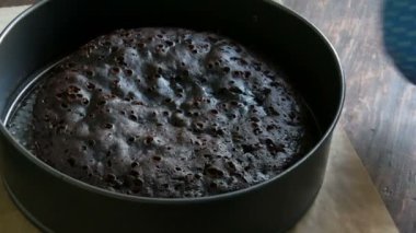 Mavi mutfak eldiveni kadın elinde taze pişmiş ev yapımı çikolatalı browni kek masanın üzerine alır.