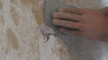 Adam eski bir spatula ile duvar kağıdı görünümü kapatın kil duvarlar temizler